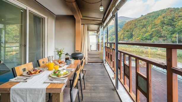 Un balcón con una mesa de comedor preparada para el desayuno, con vistas a un valle pintoresco.