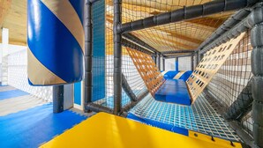 Zona de juegos con cerramiento de malla, paredes acolchadas y suelo acolchado.