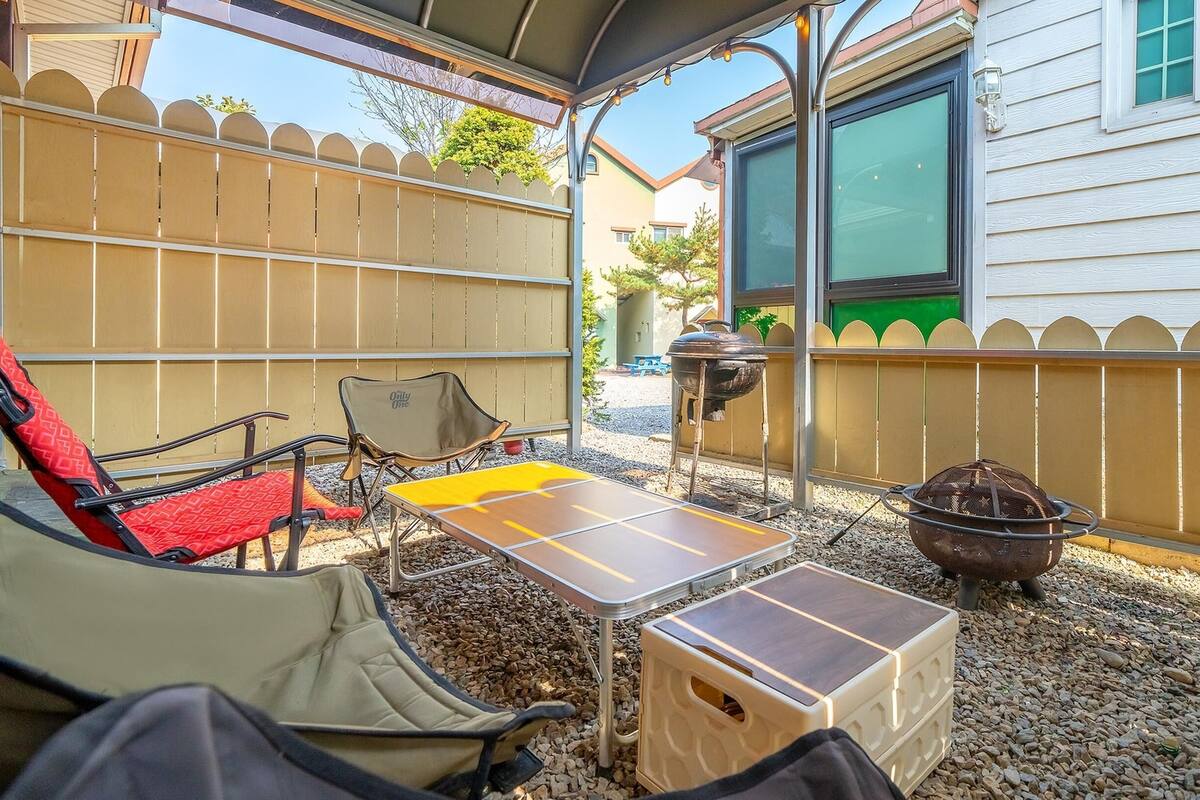 An outdoor patio area with a table, chairs, a grill, and a barbecue smoker.