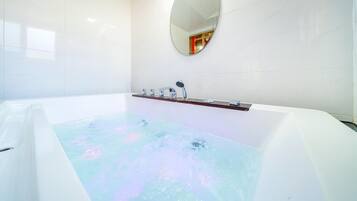 Bathroom features a large bathtub with a handheld showerhead and chrome faucet.