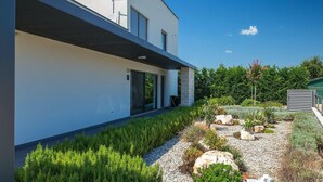 Una casa moderna su due piani con tetto piatto, ampie finestre e un pilastro in pietra.