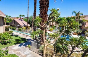 A residential area with a swimming pool, palm trees, and houses with red-tiled roofs.