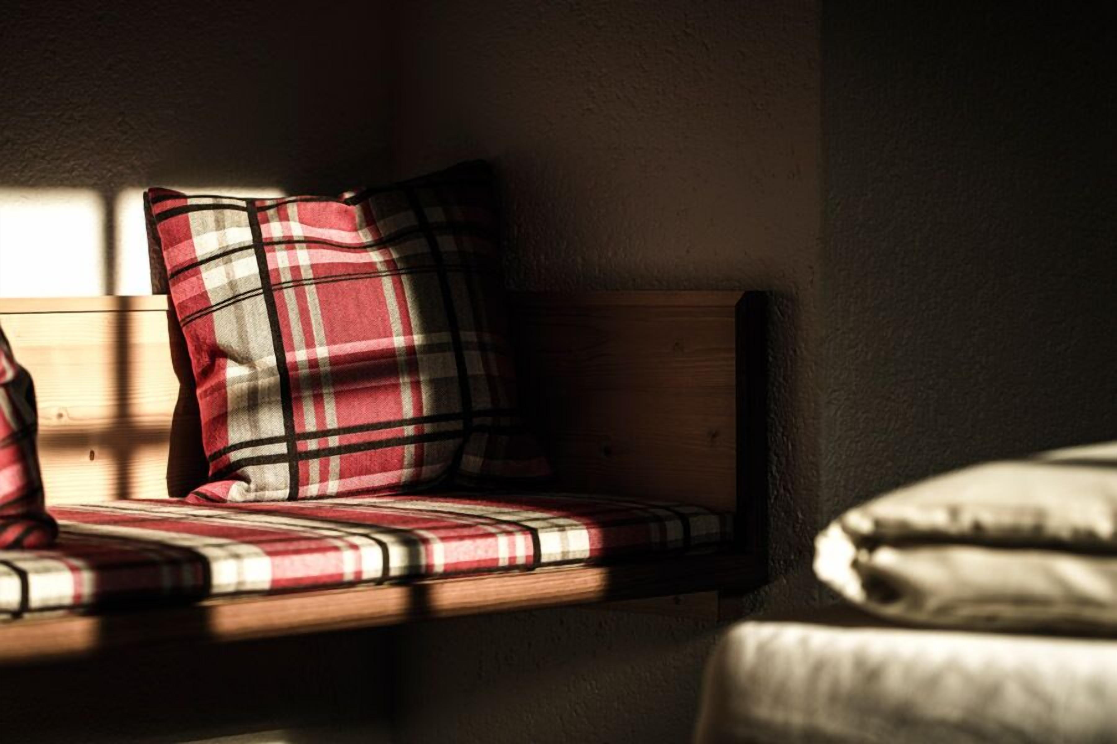 Un banco de madera con cojín de cuadros y almohada.