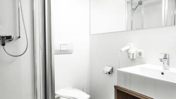 Un baño moderno con cabina de ducha de vidrio, un lavamanos blanco y un inodoro.