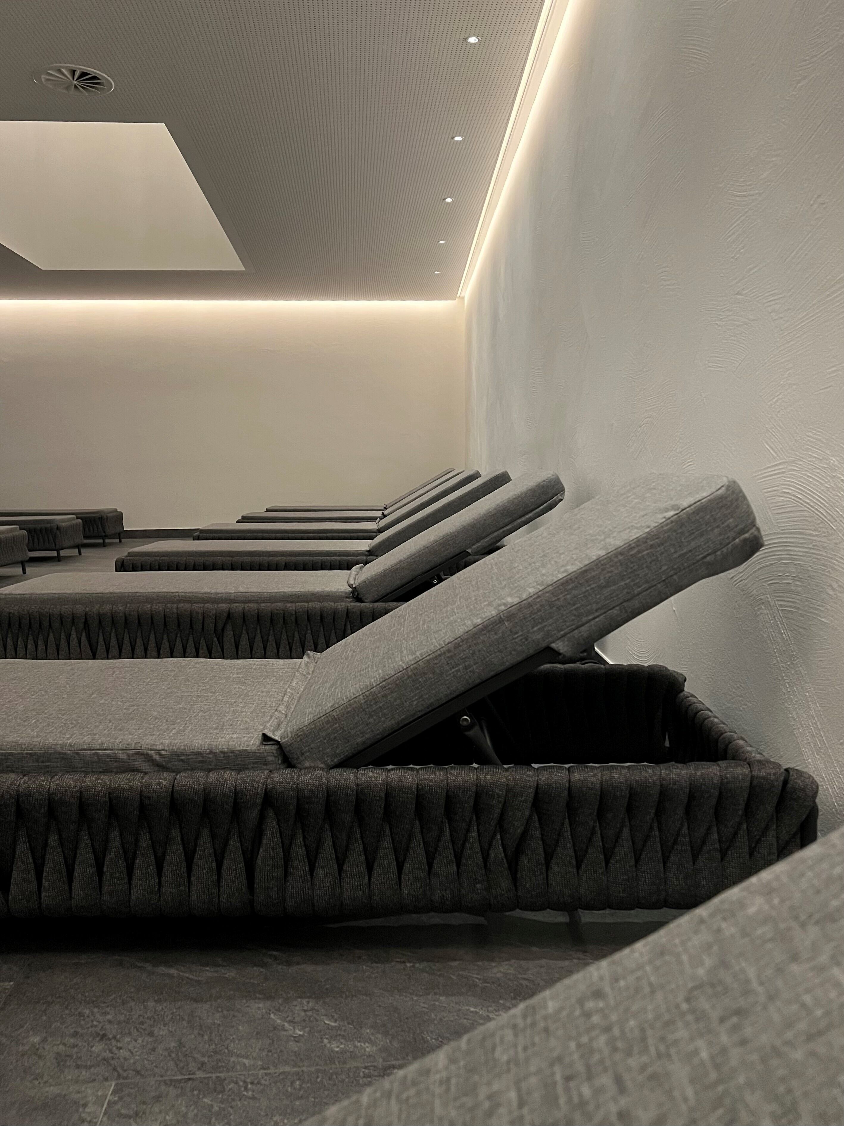 A modern relaxation room with multiple massage beds arranged in rows.