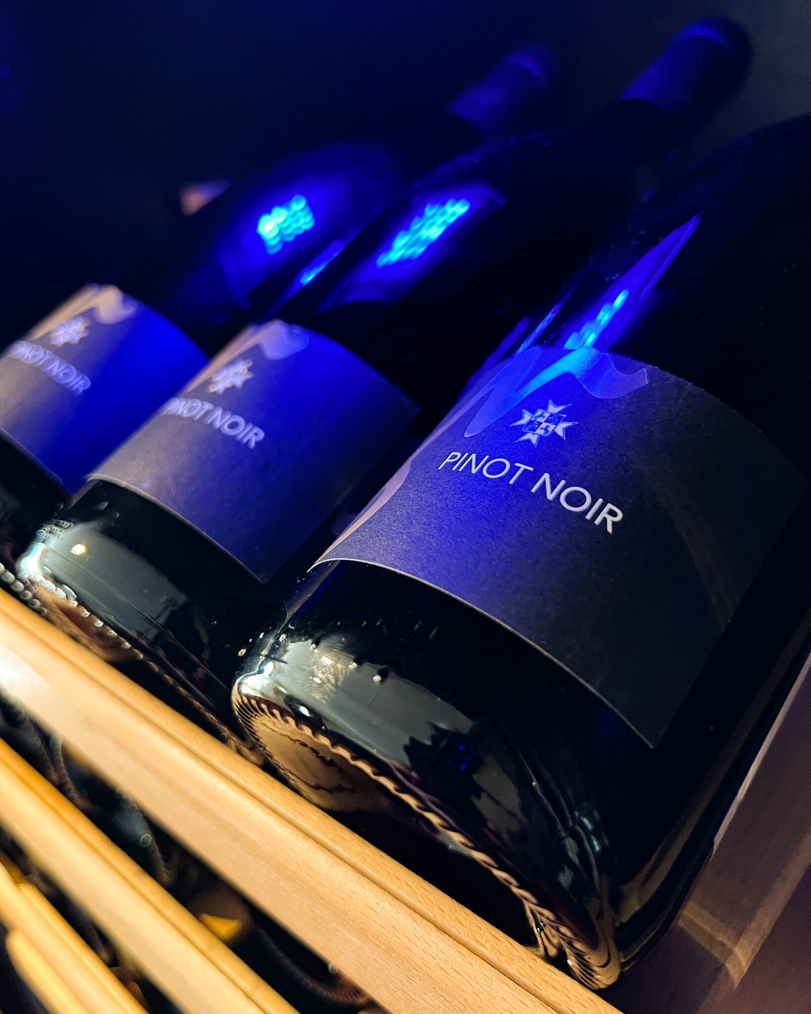 Une rangée de bouteilles de vin dont les étiquettes indiquent « PINOT NOIR » et « PINOT NOIR ».