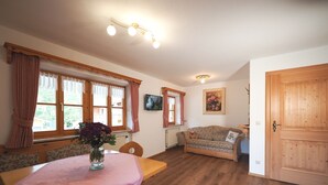 Una camera accogliente con un tavolo da pranzo in legno, un divano e una TV appesa al muro.