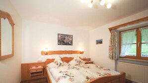 Una camera da letto con un letto di legno, due comodini, una lampada da parete, un quadro incorniciato e una finestra con tende.