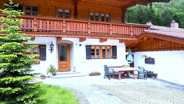 Una baita di legno con balcone, mobili da esterno e un patio in pietra.