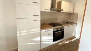 Eine moderne Küche mit weißen Schränken, einer Edelstahl-Dunstabzugshaube, einer Spüle und einem eingebauten Backofen.