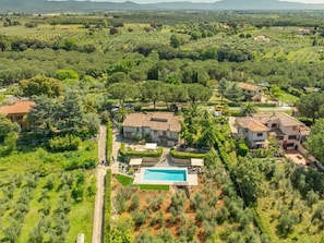 Zona residencial con varias casas, piscina y abundante vegetación.