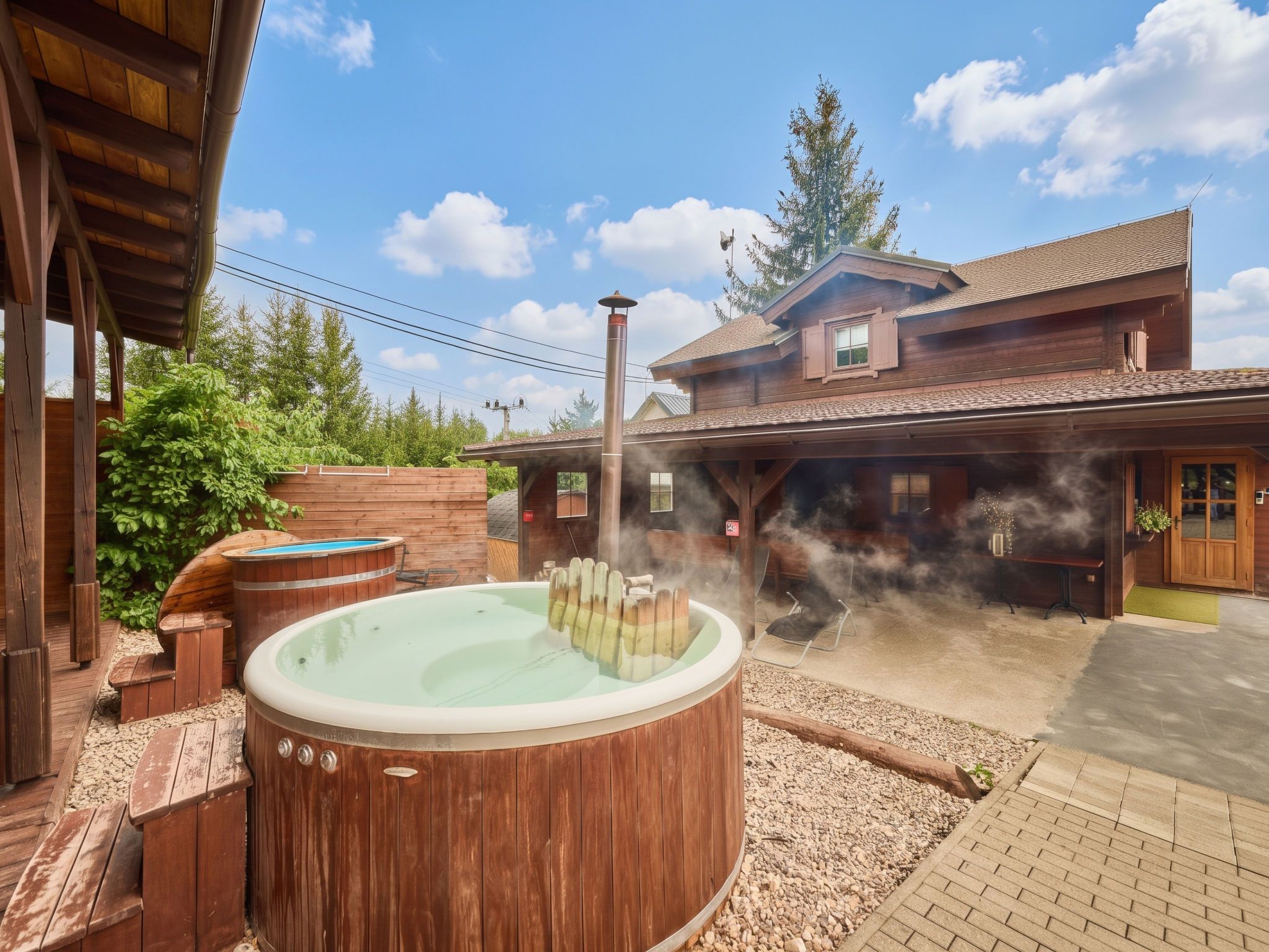 Une cabane en bois dotée d’un bain à remous et d’un sauna d’où s’échappe de la vapeur.