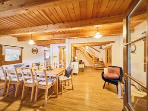 A spacious dining area with wooden furniture and a staircase leading to an upper level.