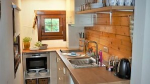 A compact kitchen with wooden cabinetry, a built-in oven, and a window above the sink. - Pod Liščím kopcem 4+4 by Interhome (Dolni Branna)