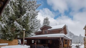 A wooden lodge with a covered patio, outdoor seating, and a hot tub. - Pod Liščím kopcem 4+4 by Interhome (Dolni Branna)