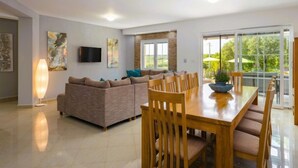 Un salón espacioso con un sofá, una mesa de comedor con sillas y un televisor montado en la pared.