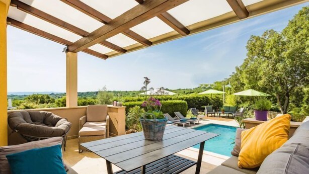 Un espacio de estar al aire libre cubierto con piscina, sillones de descanso y vistas del paisaje.