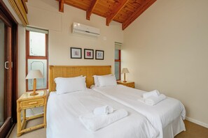 A hotel room with a double bed, two bedside tables with lamps, a large mirror, and a ceiling fan.