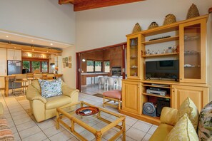 A spacious living area with a sofa, coffee table, and a wooden cabinet with glass doors. - San Lameer Villa 14117 (Southbroom)