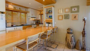 A modern kitchen with a wooden dining table, metal chairs, and a variety of decorative items on the walls.