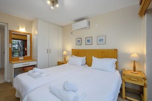 Ein Hotelzimmer mit Bett, Schreibtisch, Spiegel und Wandklimaanlage.