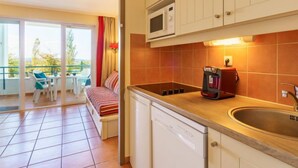 A kitchen with a microwave, coffee maker, and sink. There is a balcony with a sofa and chairs. - Les Terrasses d'Arcangues by Interhome (Arcangues)