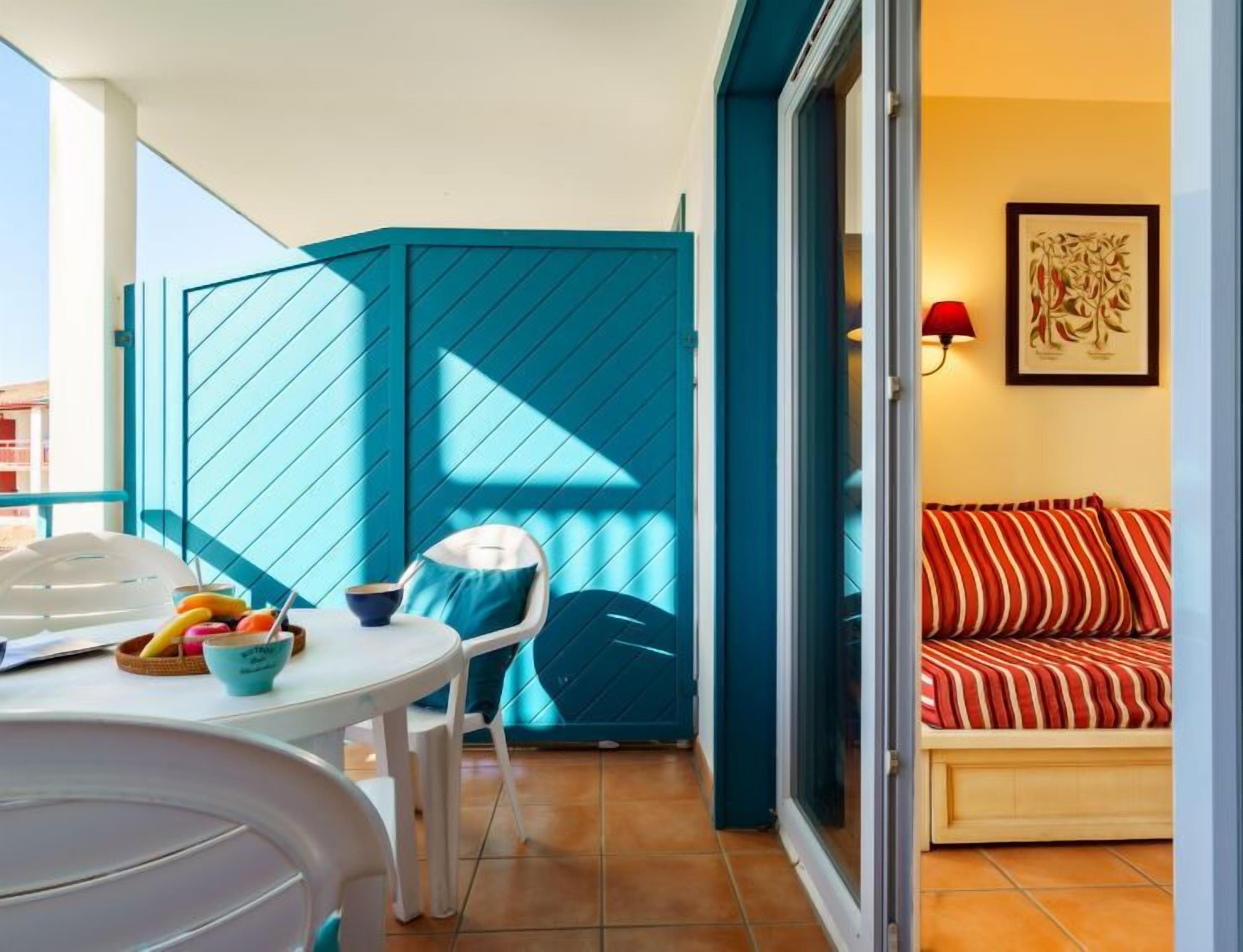 Ein Balkon mit Tisch, Stühlen und einer kleinen Sitzecke mit gestreifter Auflage.