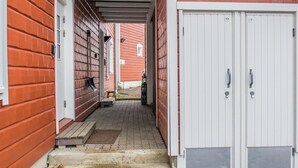 A narrow corridor with a wooden door on the right and a red brick wall on the left.