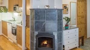 A kitchen with a stone fireplace, wooden cabinets, a microwave, and a sink.
