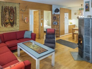 En hyggelig stue med en rød sofa, en grå lænestol og et sofabord med en dekorativ tallerken. En pejs ses i baggrunden.