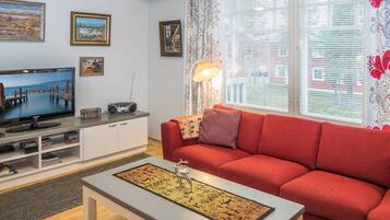 Un salon comprenant un téléviseur, un canapé, une table basse et des objets de décoration.