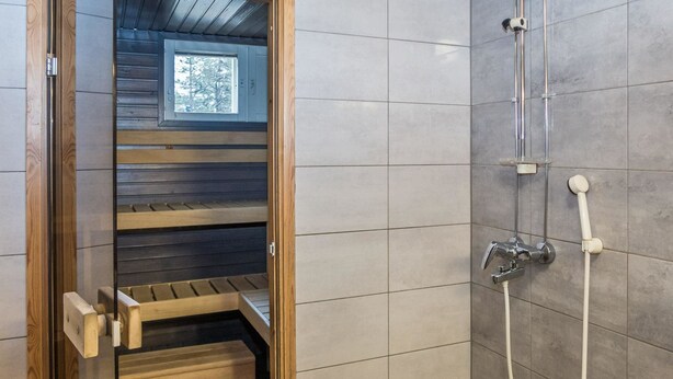 A modern bathroom with a wooden shower enclosure, tiled walls, and a visible window.