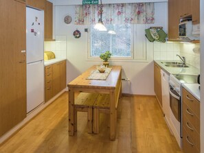 A compact kitchen with wooden cabinets, a dining table, and a window with a view.