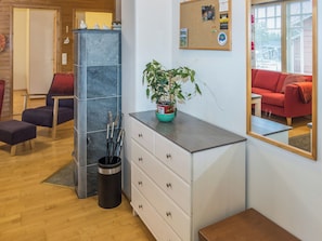 A reception area with a desk, drawers, a potted plant, a bulletin board, and a red couch.
