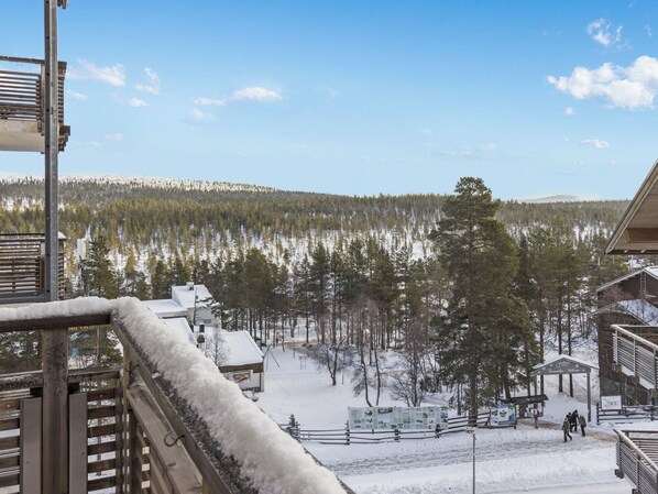 Et sneklædt landskab med udsigt til et skovområde og en bygning med et skilt, der står 'Hotel'.