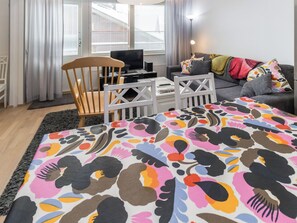 A modern living room with a sofa, a chair, a TV, and a patterned rug.