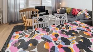 A modern living room with a sofa, a TV, and a patterned rug.