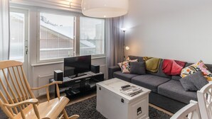 A modern living room with a television, sofa, and a rocking chair.