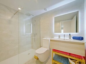 A modern bathroom with a glass shower enclosure, a toilet, and a vanity with a mirror. - Essential Javea by Interhome (Jávea)