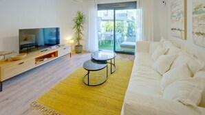 Un salon moderne avec un canapé, un téléviseur, une table basse et une plante.