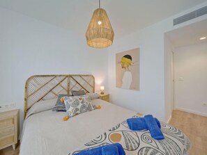 A bedroom with a bed, bedside table, and a hanging light fixture. - Essential Javea by Interhome (Jávea)