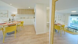 Un intérieur moderne comprenant un coin repas, une cuisine et un grand miroir.