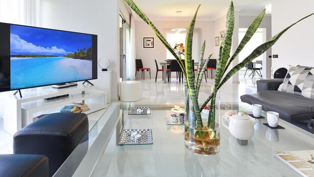A modern living room with a flat-screen TV, a glass coffee table, and a sofa. - Meloneras Hills 19 by Interhome (Maspalomas)