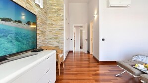 A modern living room with a flat-screen TV, a sofa, and a dining table. - Meloneras Hills 19 by Interhome (Maspalomas)