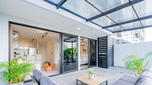A modern living space with a glass door leading to a kitchen, a sofa set, a small table, and potted plants. - w* | Glorious 1BR w/ Terrace in San Francisco (Panamá)