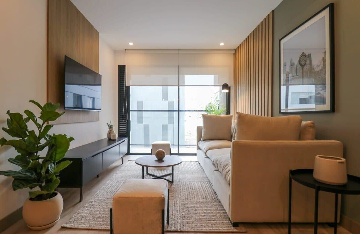 Un salon moderne avec un canapé, une table basse, un téléviseur et une grande fenêtre.