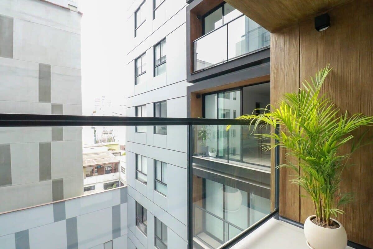 Un bâtiment moderne doté d’un balcon, de grandes fenêtres et d’une plante en pot.