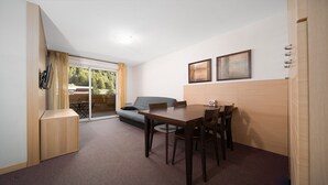A compact room with a dining table, chairs, a sofa, and a sliding glass door leading to an outdoor area. - Apt 4/6 ppl near the ski runs, mountain view (Allos)