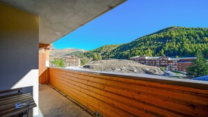 A balcony with a view of a mountainous area, wooden railings, and a building with multiple floors. - Apt 4/6 ppl near the ski runs, mountain view (Allos)