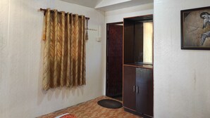 Una habitación con ventilador de techo, una puerta con cortina estampada, un armario y una obra de arte enmarcada en la pared.
